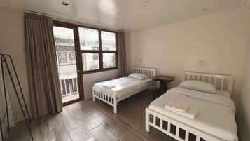 Un dormitorio con dos camas individuales, una mesita pequeña y una ventana con cortinas.