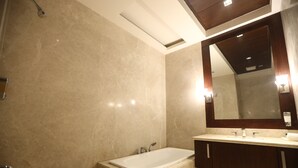 A modern bathroom with a large mirror, a bathtub, and a vanity with a sink. - Calista Resort (New Delhi)