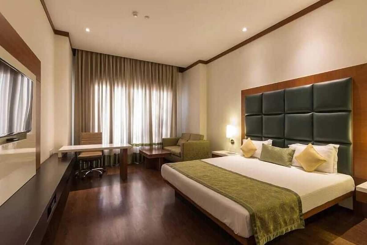 A hotel room with a large bed, a desk, a chair, and a television.