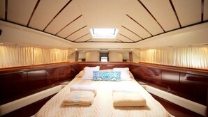 Una cabina spaziosa con un ampio letto, pannelli in legno e un lucernario.