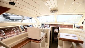 Interni di uno yacht con un pannello di controllo, una zona salotto e un piccolo tavolo.