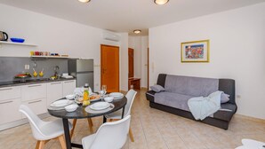 Un espacio habitable compacto con kitchenette, comedor y sofá.