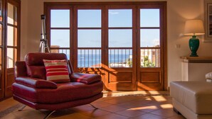 A living room with a leather armchair, a sofa, a glass coffee table, and a telescope.