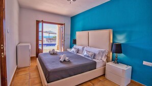 A bedroom with a bed, bedside table, and a view of the outside.