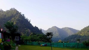 A grassy area with a colorful path leading to a building. - PRIDE INN LUXURY RESORT BY UK HEAVEN (Yamkeshwar)