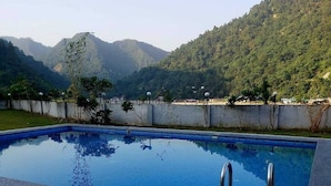 A swimming pool with metal railings, surrounded by a wooden deck. - PRIDE INN LUXURY RESORT BY UK HEAVEN (Yamkeshwar)