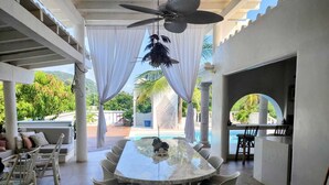 Un espacio de comedor al aire libre cubierto con una piscina al fondo.