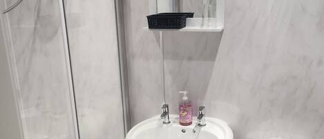 A bathroom with a white sink, a toilet, and a shower enclosure.