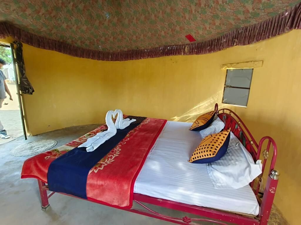 A single bed with a red metal frame, white bedding, and a red and blue blanket.