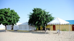 Une zone située au bord de la plage, avec des tentes blanches et un bâtiment jaune.