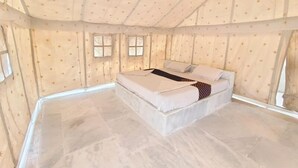 Une pièce aménagée comme une tente, avec un lit, deux fenêtres et un plafond décoré de motifs en forme d’étoiles.