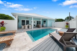 A poolside area with a covered patio, lounge chairs, and a small table. - Laid Back In Laguna - Pet Friendly, Private Pool (Panama City Beach)