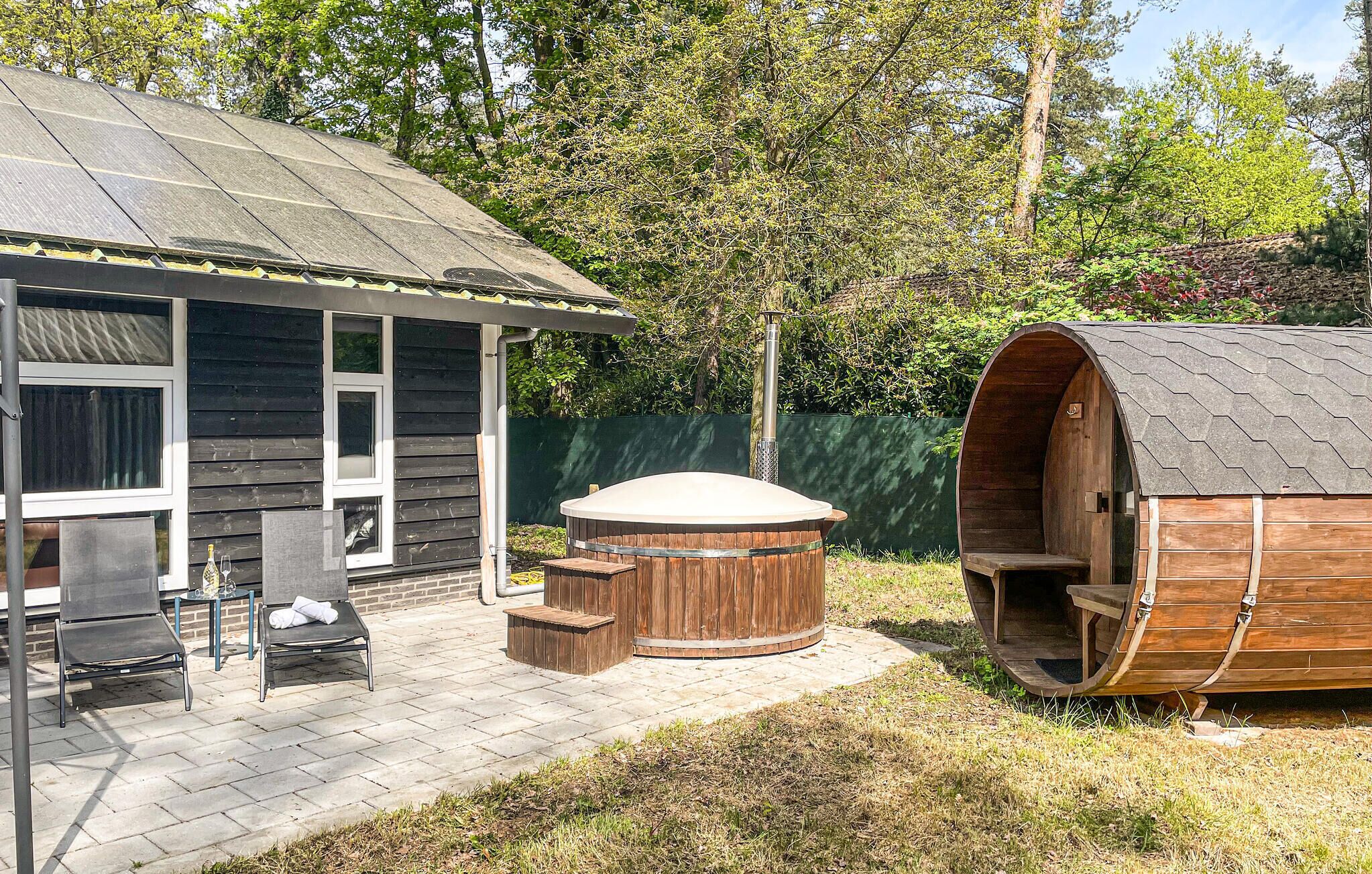 Een houten jacuzzi en een sauna in een achtertuin met een huis.