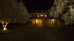 Een tweelaags huis met een verlichte veranda, een eetruimte en een zichtbare garage.