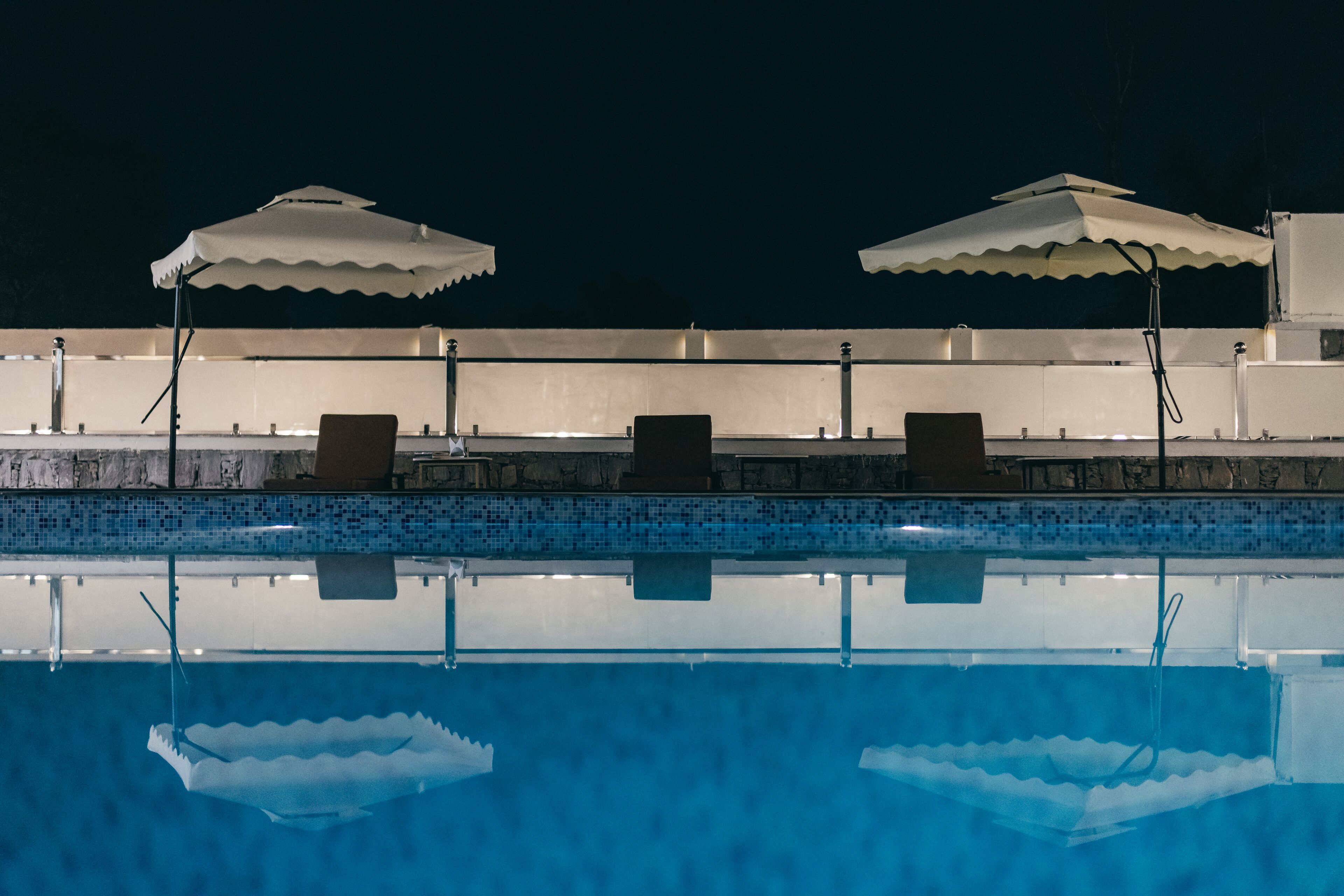 Una piscina con dos sombrillas y sillas de descanso.