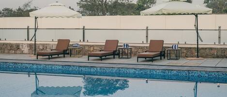 A poolside area with lounge chairs and umbrellas.