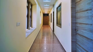 Un pasillo con piso pulido, luces empotradas y una puerta de madera a la derecha.