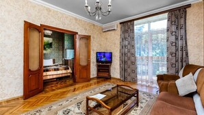 Un salon avec un canapé, un téléviseur et un lustre.
