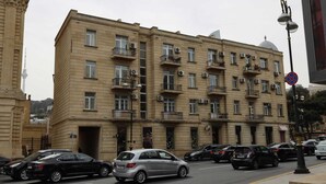 Un immeuble à plusieurs étages doté de balcons, de climatiseurs et situé devant une rue.