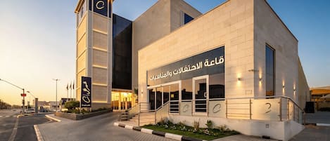 A modern building with a prominent entrance, a staircase, and a sign with Arabic text.