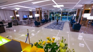 Un hall d’hôtel moderne comprenant un comptoir d’accueil, un espace salon et une grande fenêtre donnant sur la piscine.
