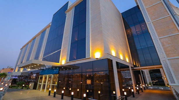 Un hôtel moderne doté de grandes baies vitrées, d’une entrée abritée et d’une façade bien éclairée.