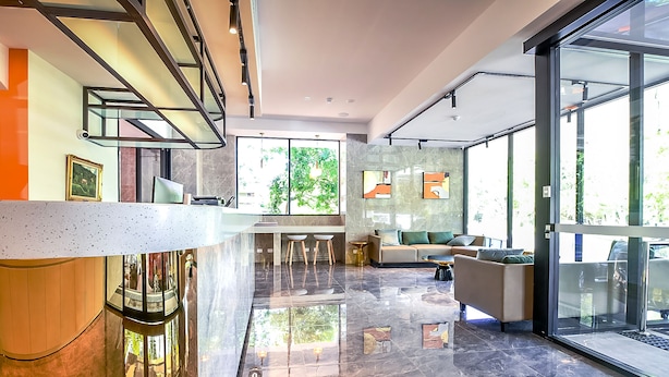 Un interior moderno con cocina, zona de estar con sofá y sillones, y ventanas amplias con vistas a zonas verdes.
