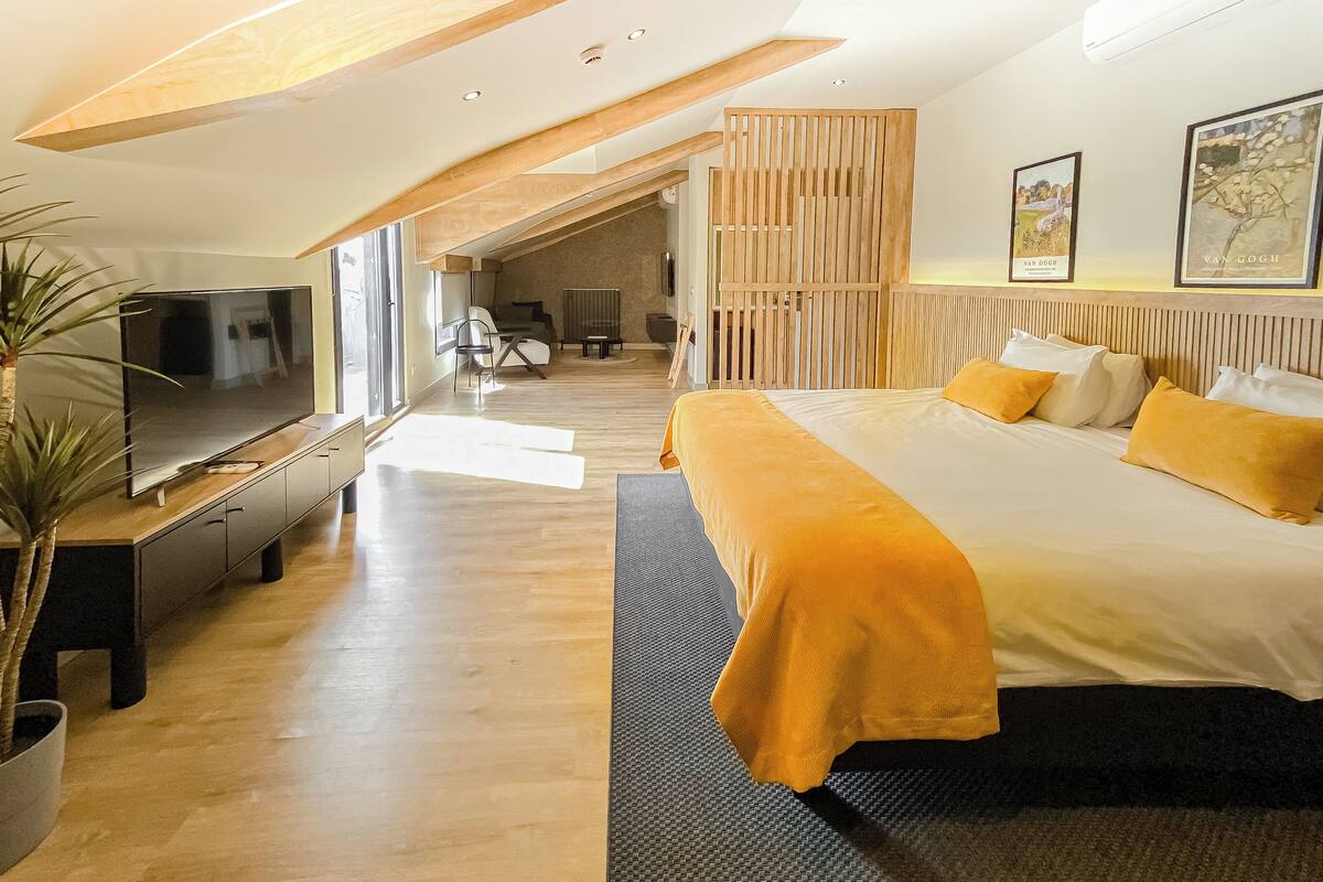 Moderni hotellihuone, jossa on suuri sänky, taulutelevisio ja näkymä ulos.