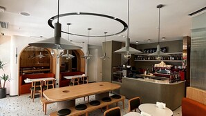 Un restaurante moderno con una mesa de madera central, rodeado de cabinas y una zona de bar.