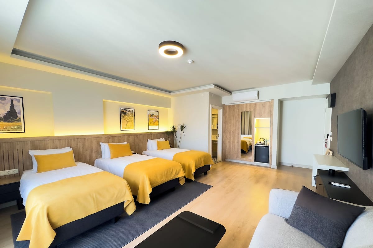 Hotellihuone, jossa on kaksi sänkyä, sohva, televisio ja työpöytä.