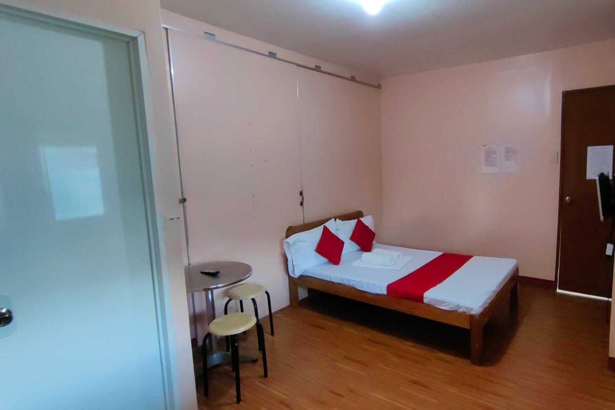 Ein kleiner, schlichter Raum mit einem Bett, einem Tischchen und zwei Hocker.
