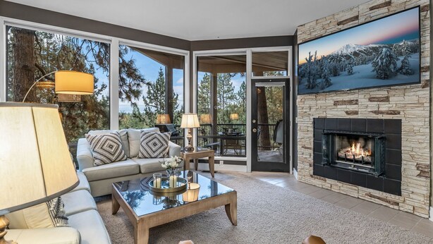 A modern living room with a fireplace, large windows, and a cozy seating area. - New Listing! Mt. Bachelor Village Condo ~ Views (Bend)