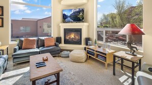 Una sala de estar con chimenea, un sofá, una mesa de centro y un televisor.