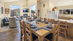 Un salón espacioso con chimenea, una mesa de comedor para seis personas y una cocina con un amplio ventanal.