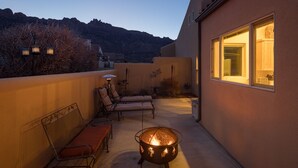 Una terraza en la azotea con un pozo de fuego, sillones de descanso y un área de comedor con vistas a las montañas.