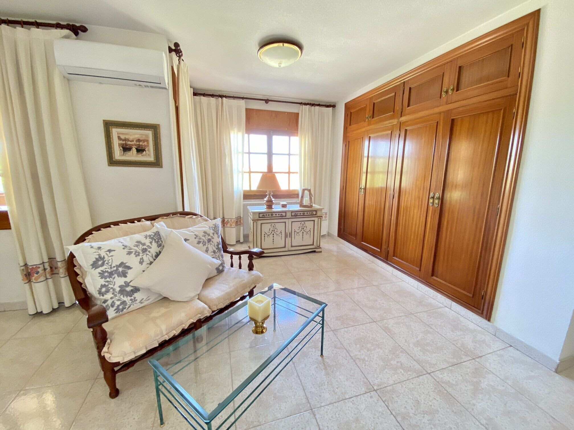 A living room with a sofa, a glass coffee table, a cabinet, and a wardrobe.
