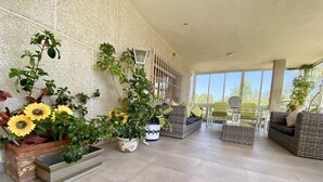 A spacious indoor area with tiled flooring, wicker furniture, and potted plants including sunflowers. - Magnifica Villa 5 Bed La Font With Private Pool (Sant Joan d'Alacant)