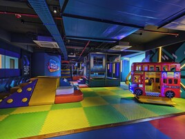 An indoor play area with a slide, padded play structures, and a toy bus.