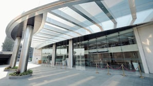 A modern building with a curved glass facade and a series of columns. - Regenta - The World Surat (Surat)