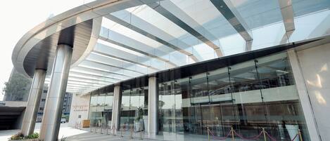A modern building with a curved glass facade and a series of columns.