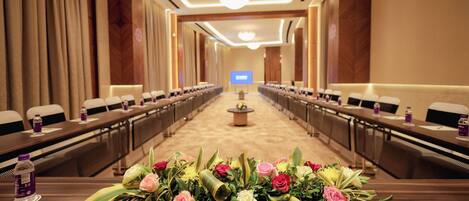 A conference room with a long table, chairs, and floral centerpieces.