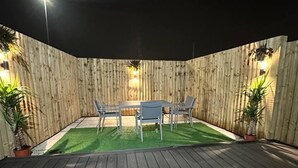 A wooden deck with a table and chairs, surrounded by a wooden fence and potted plants. - Immaculate 4-bed Detached House in Bootle (Bootle)