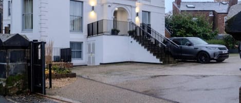 Un edificio blanco de dos pisos con una escalera negra que lleva a la entrada.