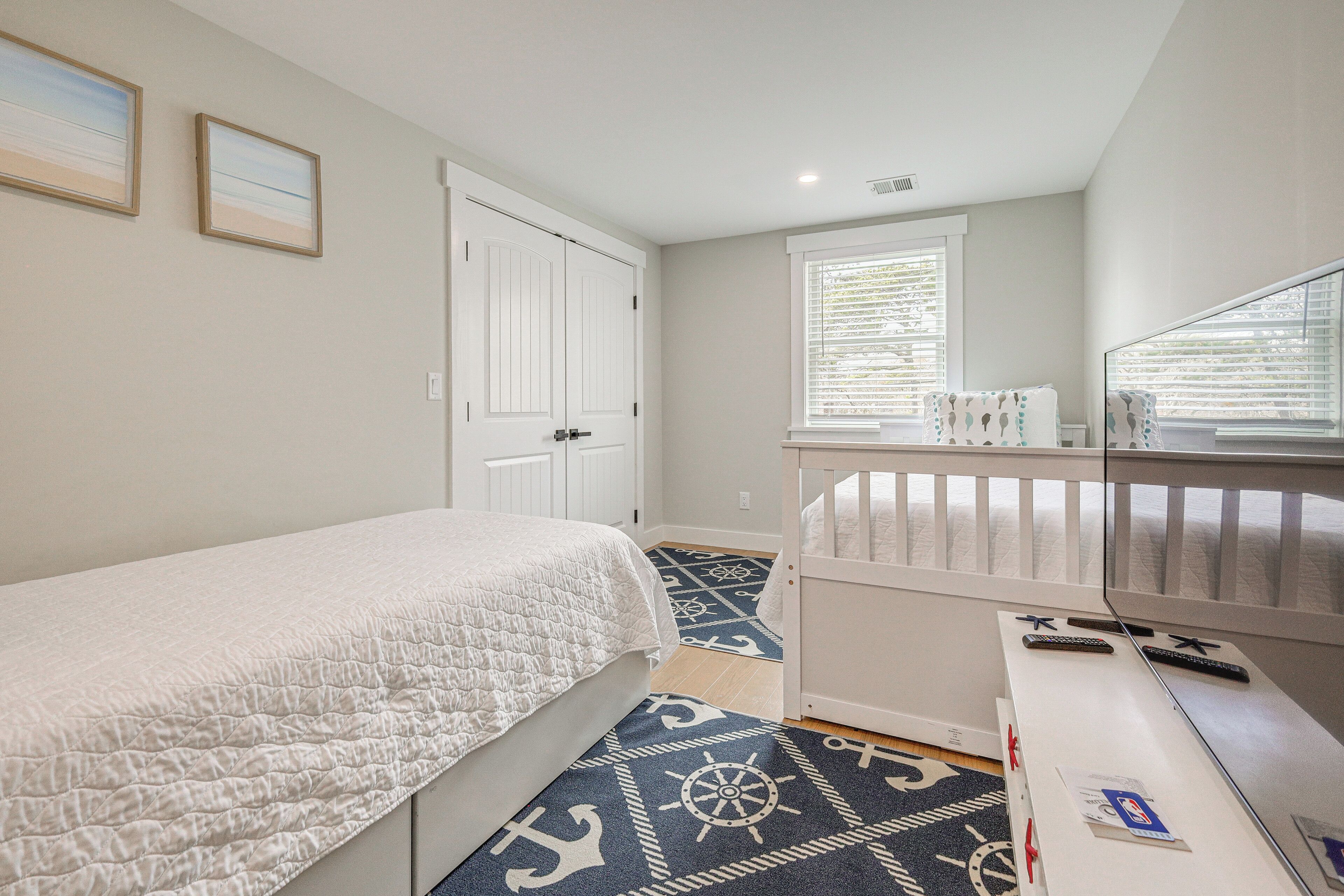 A bedroom with a bed, a dresser, a mirror, a window with blinds, and a door.