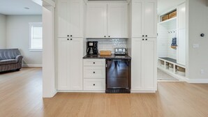 A modern kitchen with white cabinetry, a built-in dishwasher, and a countertop with a coffee maker.