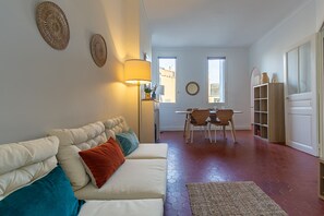 A living room with a sofa, a lamp, a dining area with chairs and a table, and a bookshelf. - Charming apartment in an elegant Marseille building (Marseille)