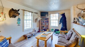 A cozy living room with a wooden table, a sofa, and a bear statue. - Reservoir & Dock Access: Pet-friendly Kerens Cabin (Kerens)