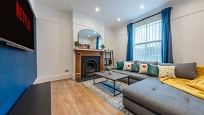 A modern living room with a fireplace, a sofa, a coffee table, and a TV screen displaying the Netflix logo. - West London Period Home (London)