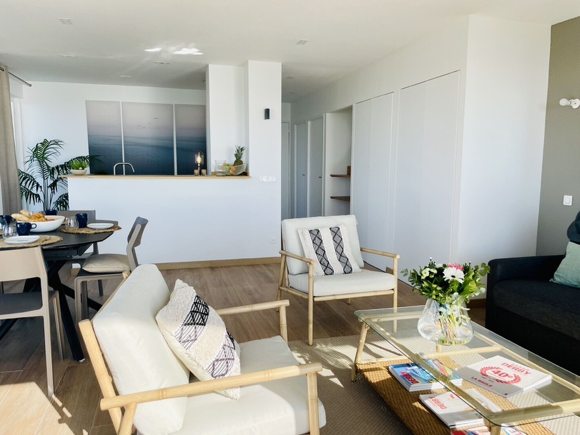 Una sala de estar moderna con comedor, un sofá y una mesa de centro con revistas.