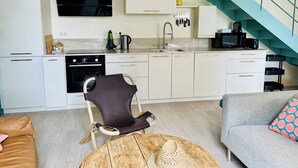 Una cocina moderna con armarios blancos, una estufa negra y una escalera color turquesa.